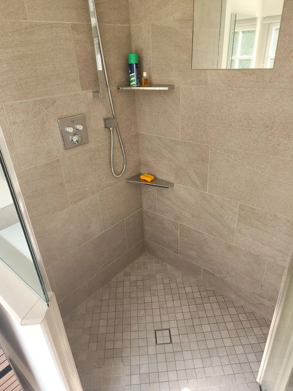 Finished shower with beige tile and mosaic floor